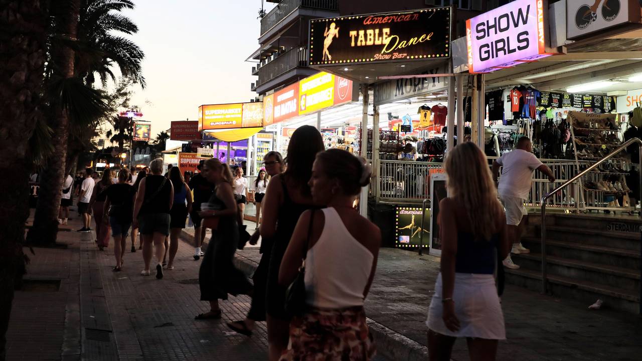 Palma: Menschen spazieren auf der Strandpromenade von Arenal auf Mallorca an Show-Bars vorbei.