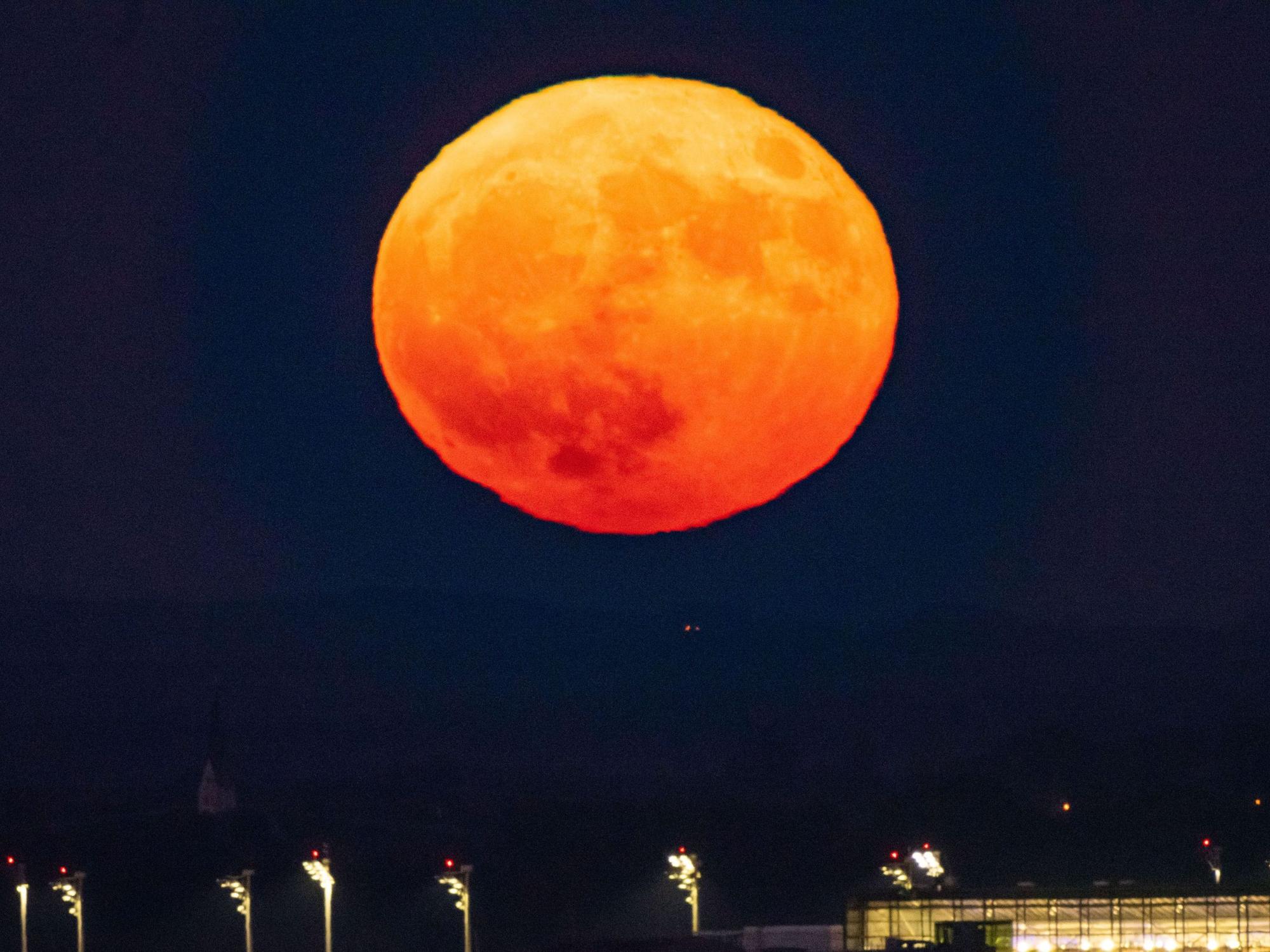 Der Vollmond geht am Abend über dem Flughafen München im Hallbergmoos auf.