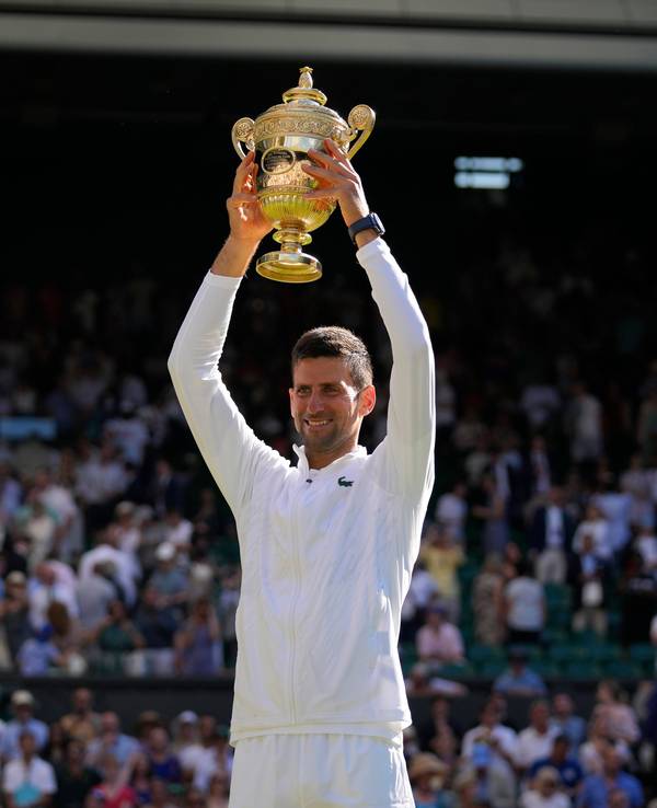 Novak Djokovic hält die Wimbledon-Trophäe über seinem Kopf.