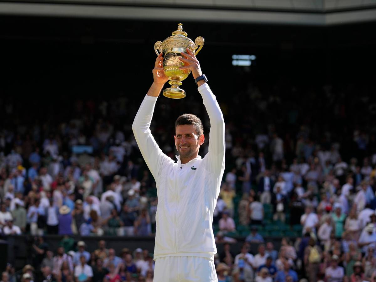 Novak Djokovic hält die Wimbledon-Trophäe über seinem Kopf.