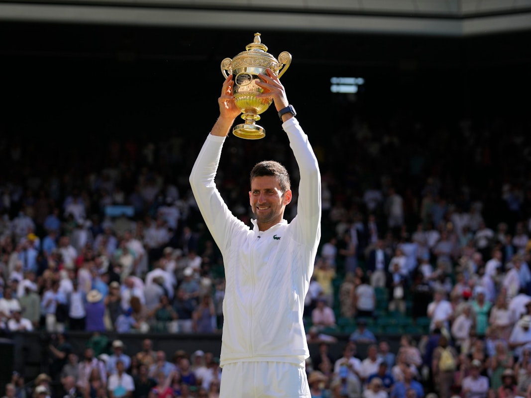Novak Djokovic hält die Wimbledon-Trophäe über seinem Kopf.