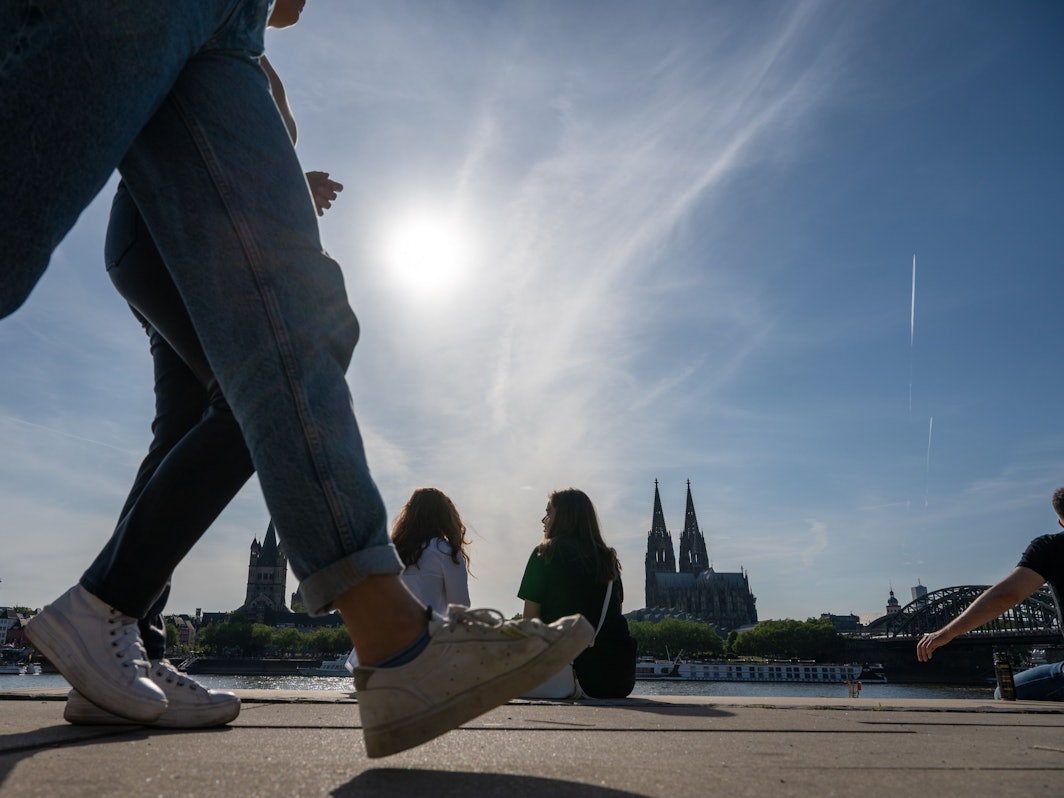 Am Rheinboulevard flanieren junge Leute durch den Sonnenschein.