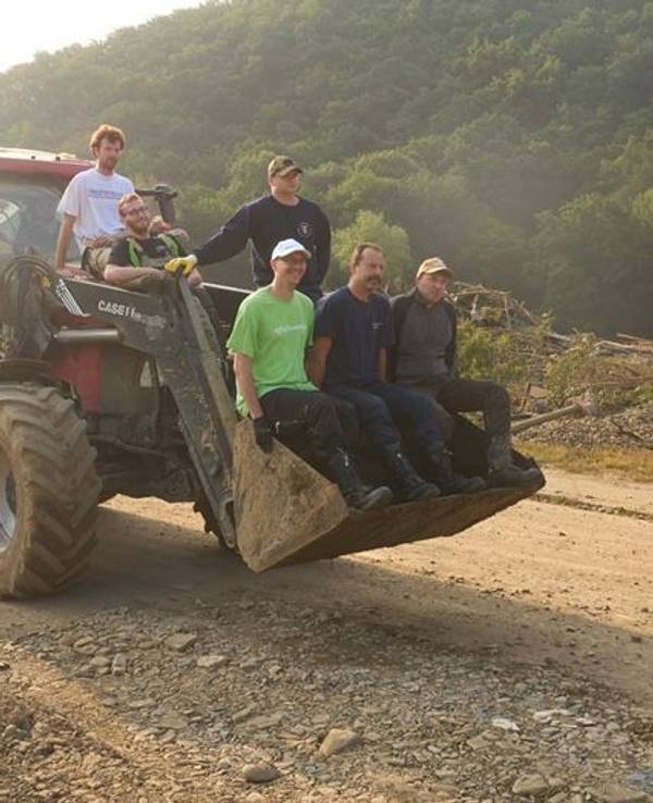 Helfer der Flutkatastrophe in NRW und Rheinland-Pfalz sitzen auf einem Bagger.