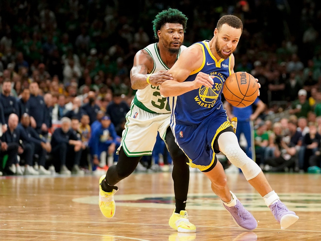 Stephen Curry (r) führt den Ball und wird von Marcus Smart (l) gestört.