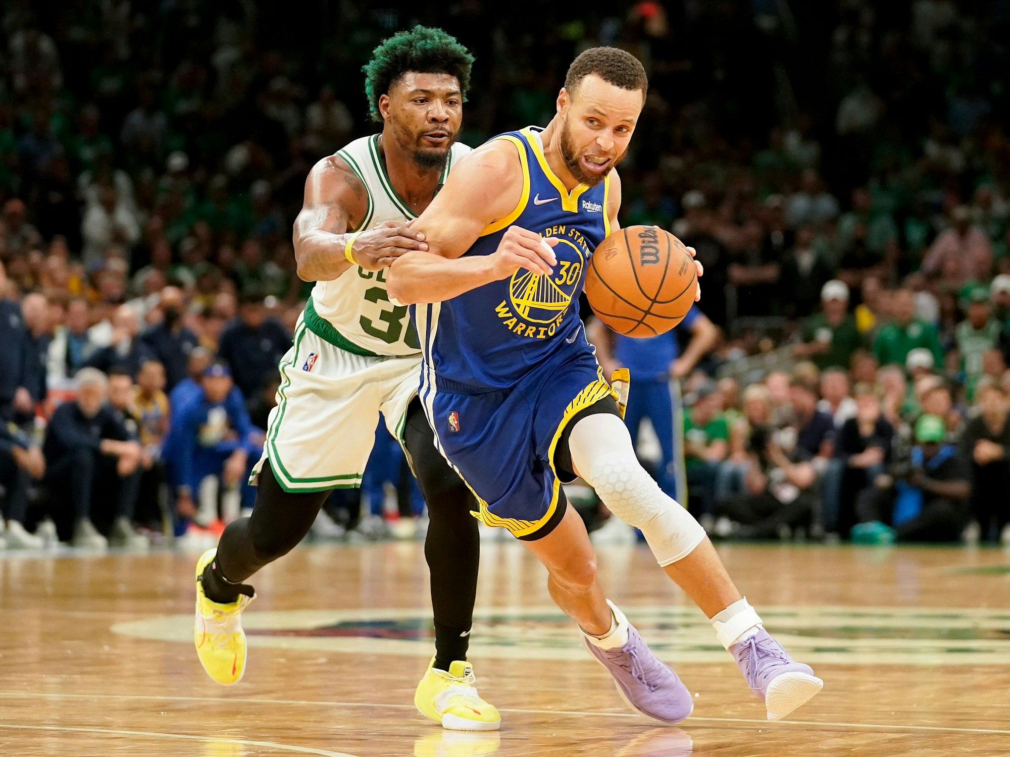 Stephen Curry (r) führt den Ball und wird von Marcus Smart (l) gestört.