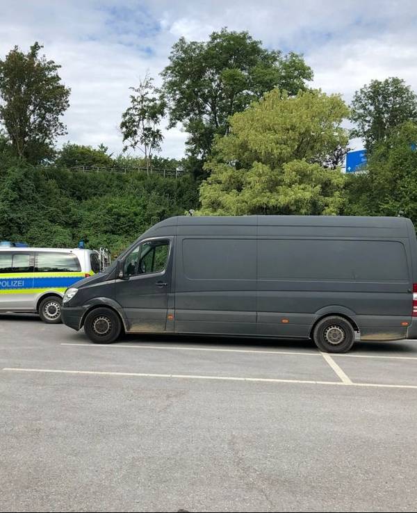 Ein überladener Mercedes Sprinter steht hinter einem Polizeiwagen auf einem Parkplatz.