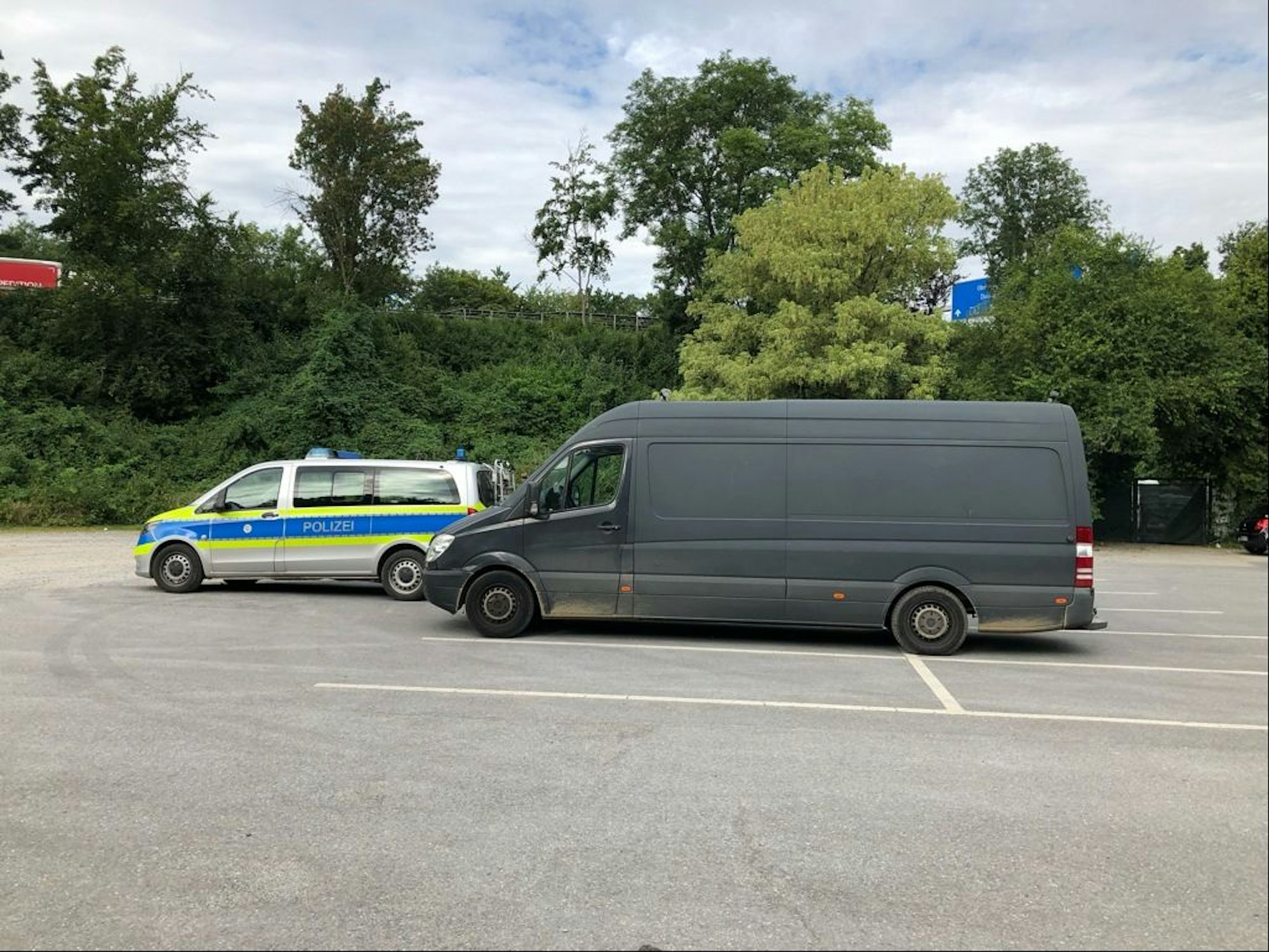 Ein überladener Mercedes Sprinter steht hinter einem Polizeiwagen auf einem Parkplatz.