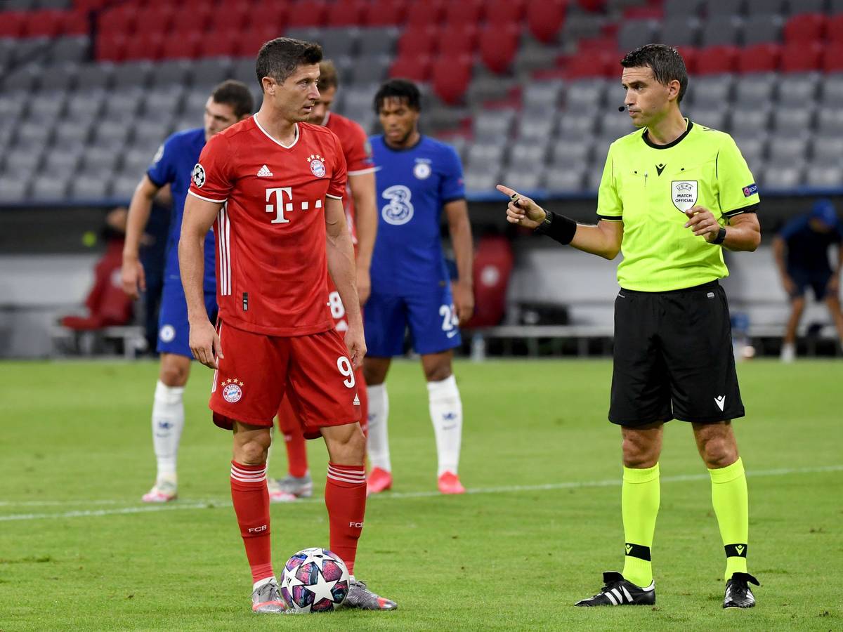 Bayern Münchens Robert Lewandowski steht neben Schiedsrichter Ovidiu Hațegan aus Rumänien vor seinem Elfmeter.