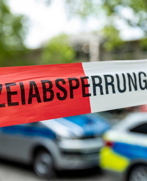 Hinter Flatterband stehen zwei Fahrzeuge der Polizei.