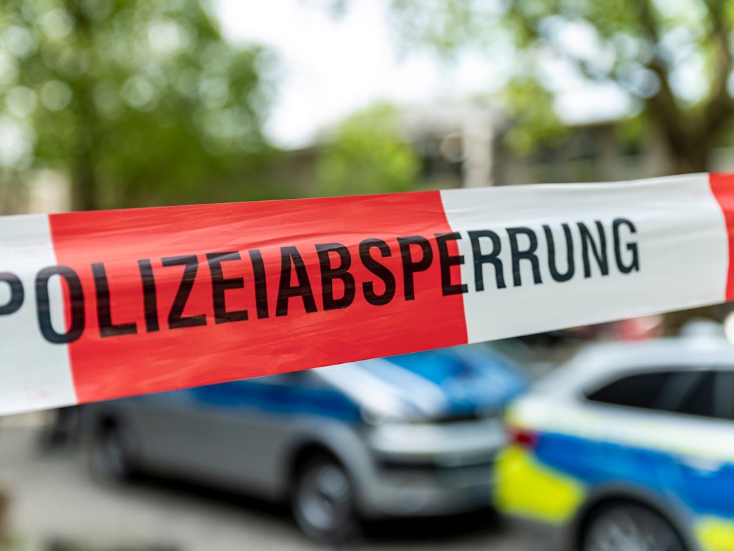 Hinter Flatterband stehen zwei Fahrzeuge der Polizei.