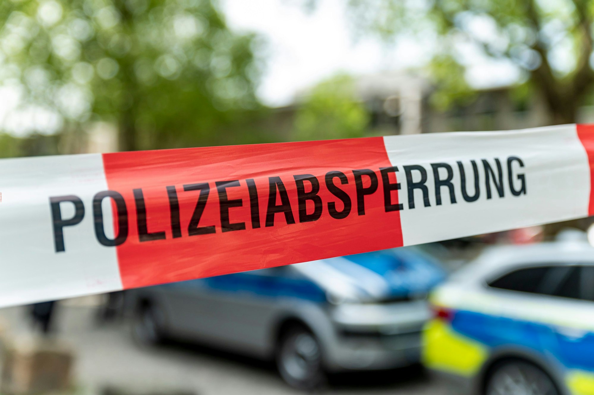 Hinter Flatterband stehen zwei Fahrzeuge der Polizei.
