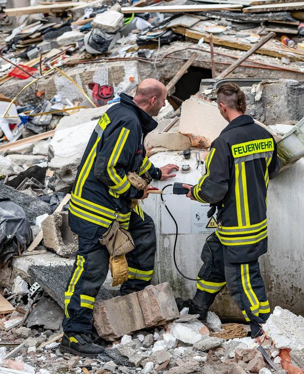Feuerwehrleute machen eine Messung an einem Gastank zwischen den Trümmern nach einer Hausexplosion in Hemer.