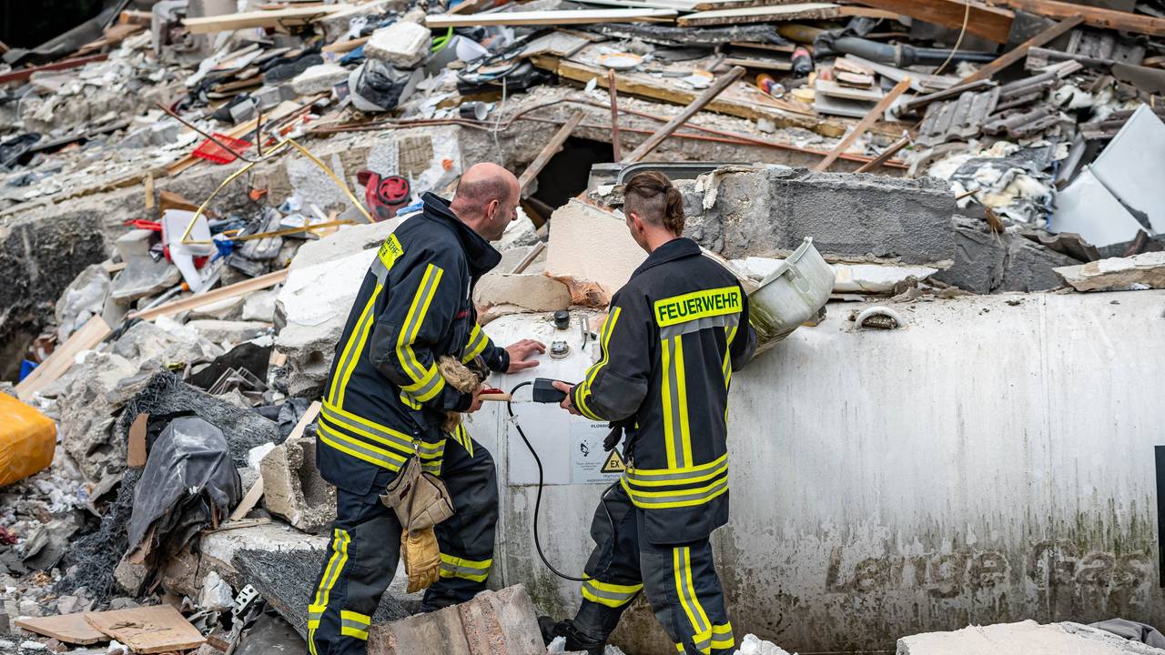 Feuerwehrleute machen eine Messung an einem Gastank zwischen den Trümmern nach einer Hausexplosion in Hemer.