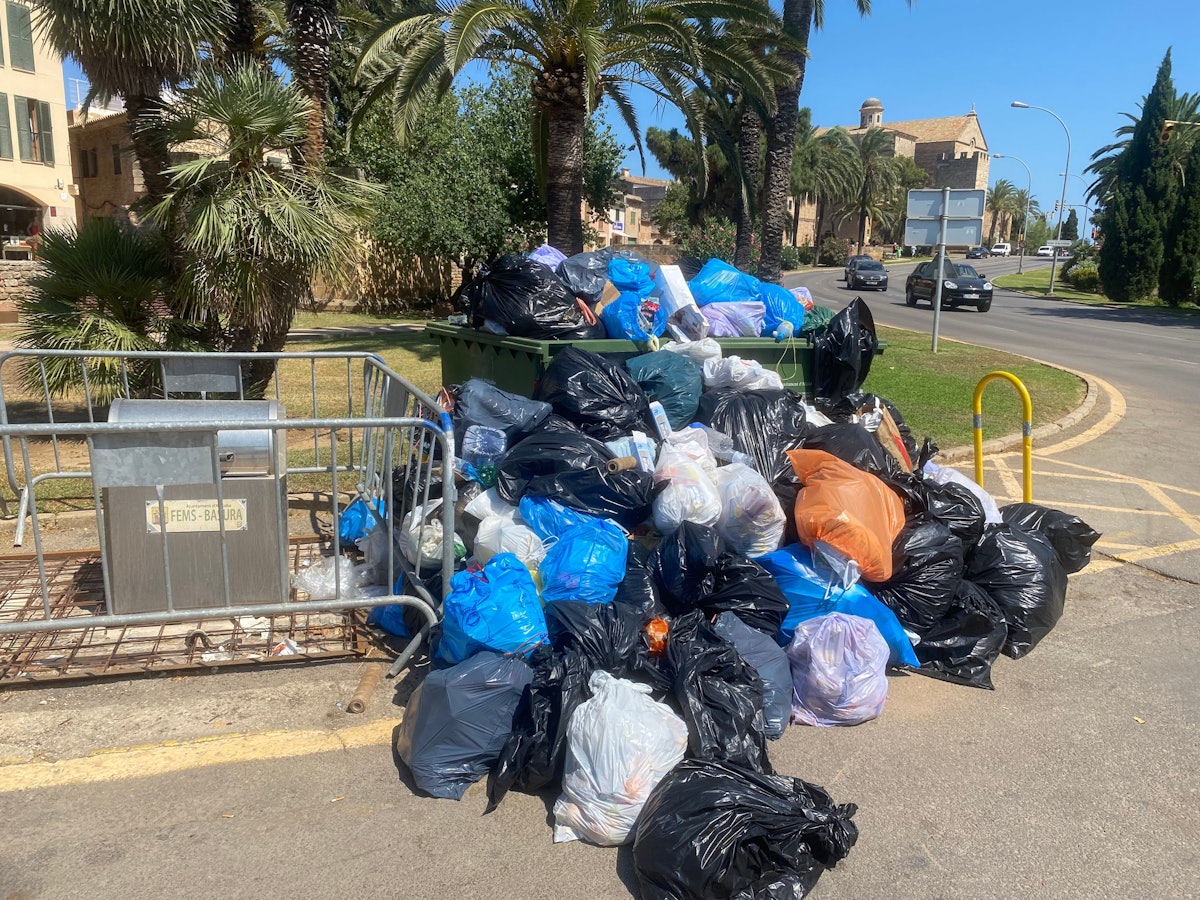 Sich stapelnde Müllsäcke vor einer überfüllten Mülltonne in Port d'Alcúdia auf Mallorca am 14. Juli 2022.