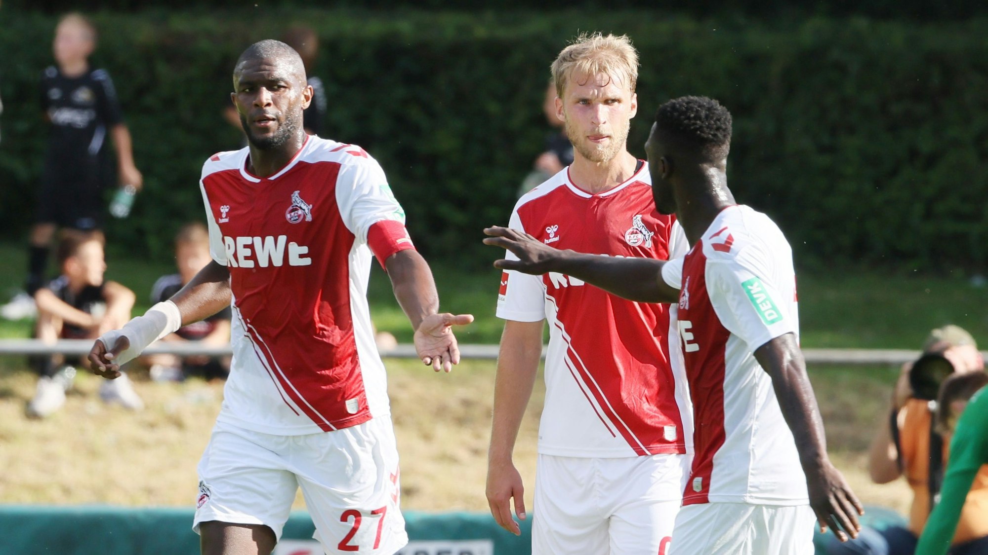 Die FC-Angreifer Anthony Modeste (l.) und Sebastian Andersson jubeln mit Kingsley Schindler (r.) beim Testspiel gegen den TuS Mondorf am 1. Juli 2022.