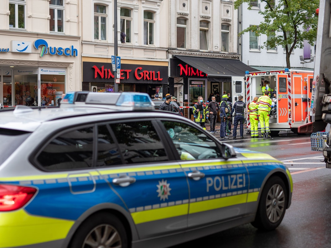 Einsatzkräfte stehen bei einem Polizeieinsatz vor einem Fast-Food -Laden auf der Kalker Hauptstraße, während ein Verletzter in einem Rettungswagen (RTW) behandelt wird.