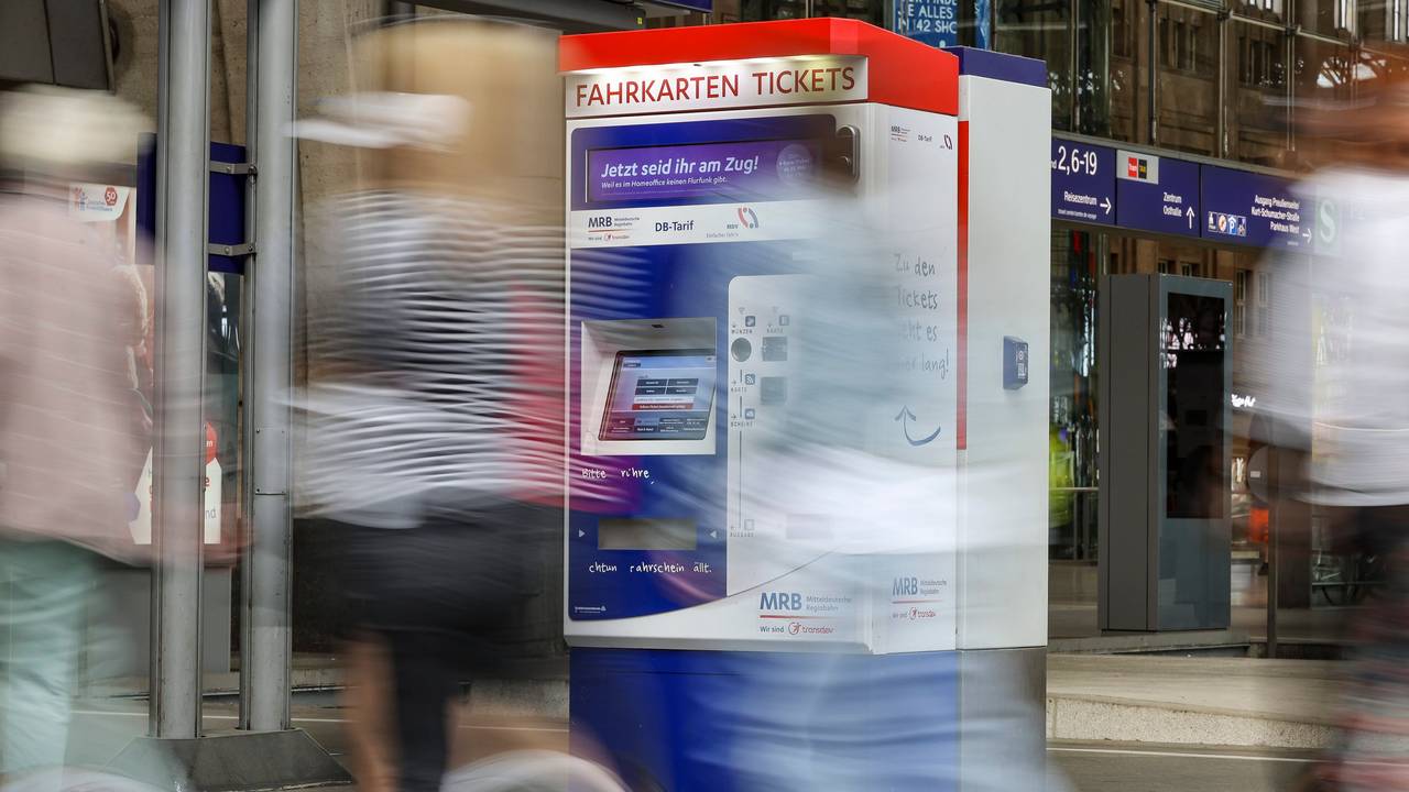 Reisende gehen an einem Fahrkartenautomaten vorbei