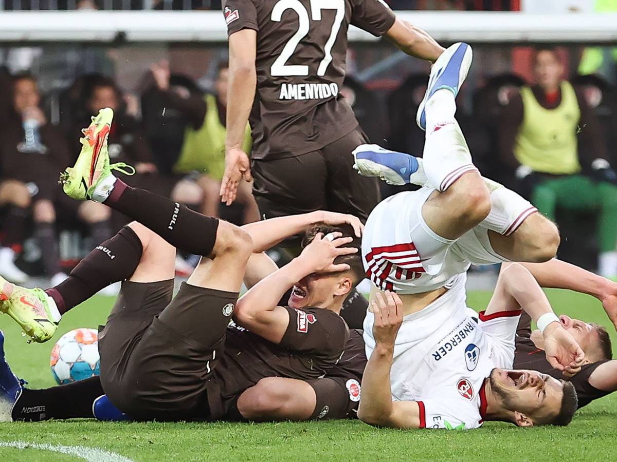 Spieler vom FC St. Pauli und vom 1. FC Nürnberg liegen nach einem Zusammenstoß auf dem Rasen.