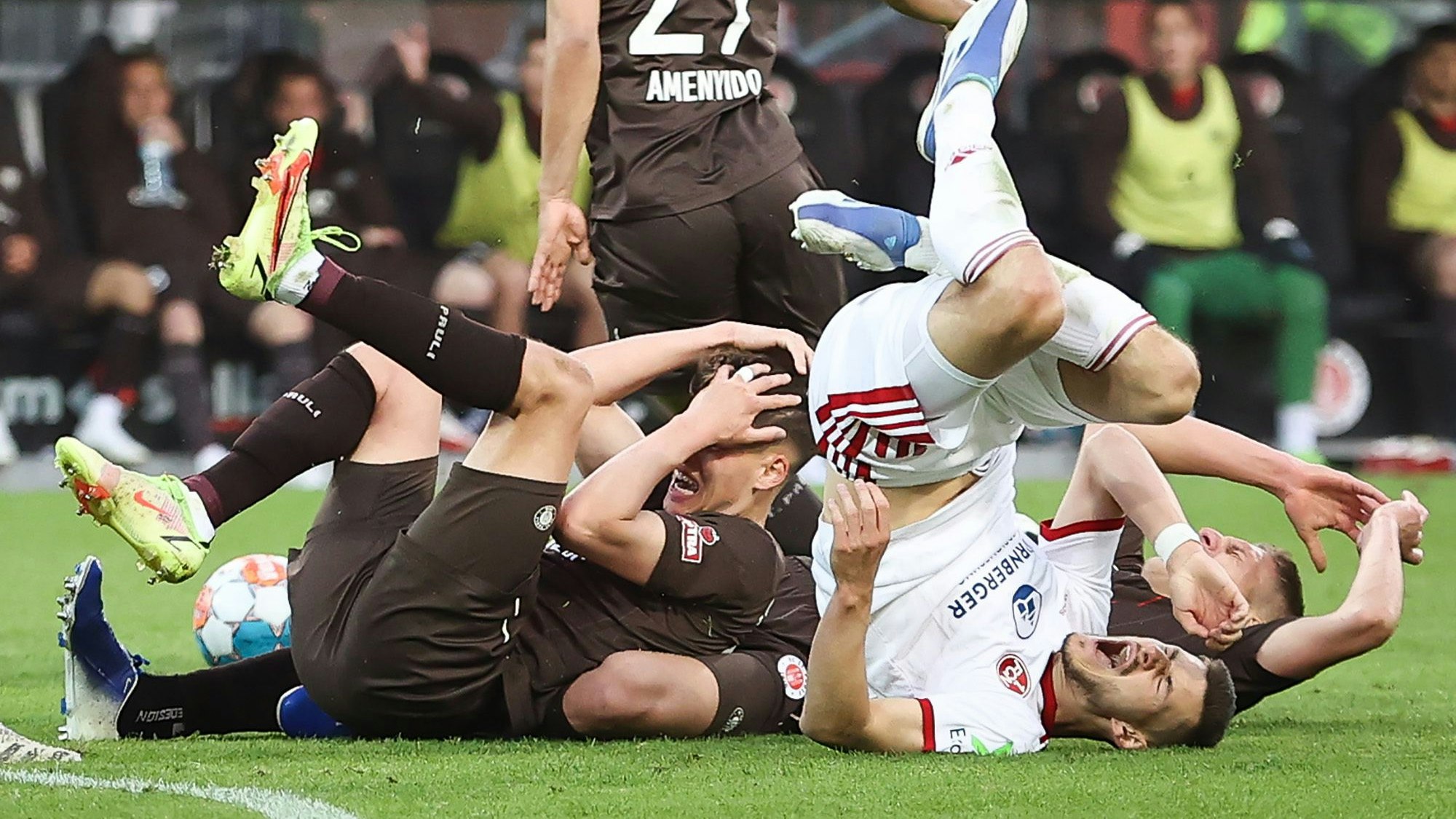 Spieler vom FC St. Pauli und vom 1. FC Nürnberg liegen nach einem Zusammenstoß auf dem Rasen.