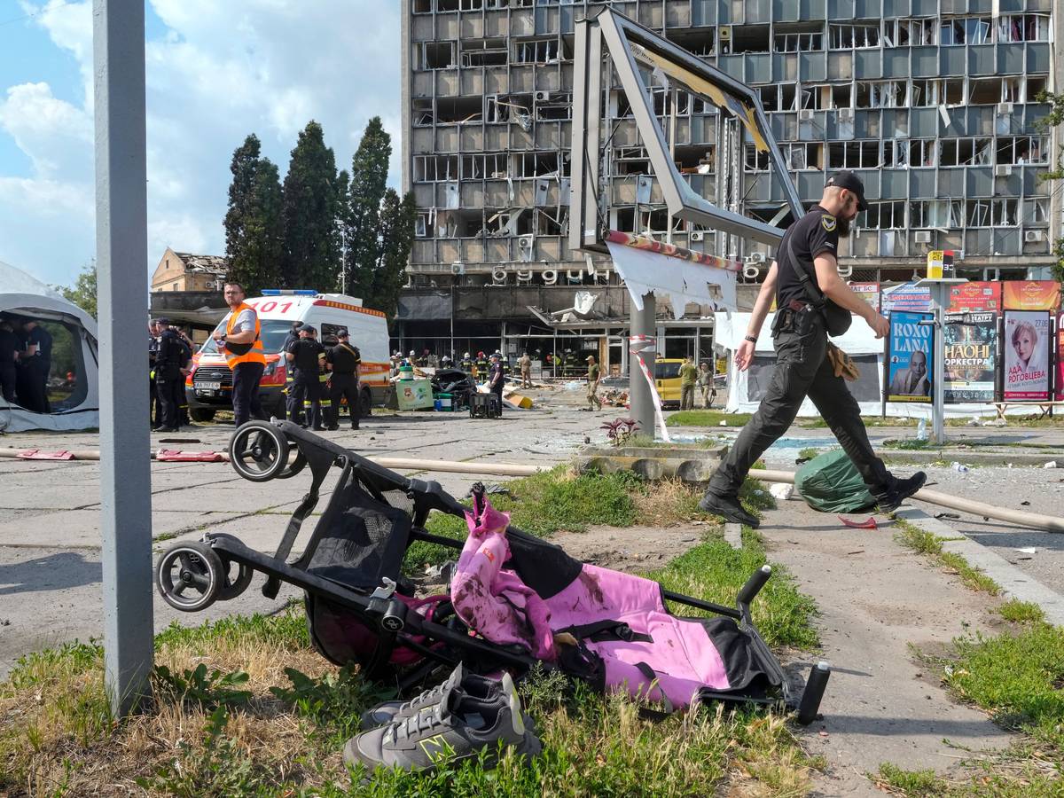 Ein mit Blut verschmierter Kinderwagen, im Hintergrund ein durch russische Bomben zerstörtes Haus. Hätte der ukrainische Präsident das wirklich verhindern können, fragt unsere Kollegin.