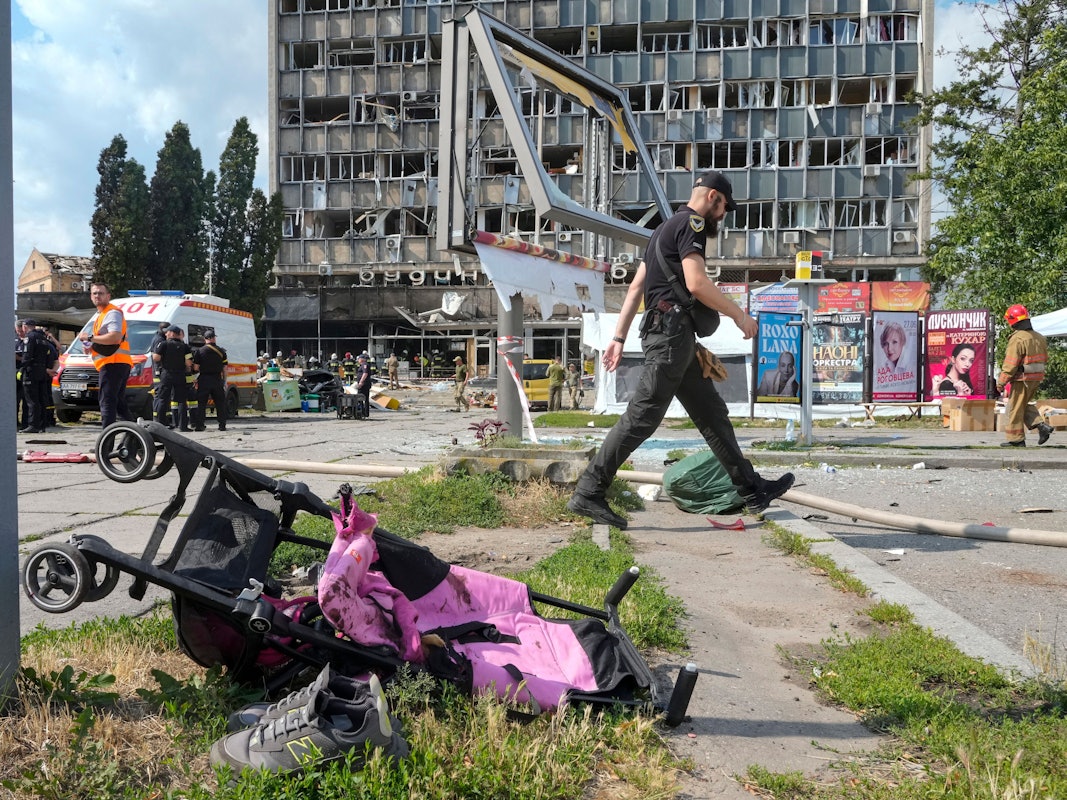 Ein mit Blut verschmierter Kinderwagen, im Hintergrund ein durch russische Bomben zerstörtes Haus. Hätte der ukrainische Präsident das wirklich verhindern können, fragt unsere Kollegin.