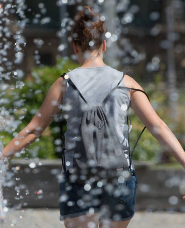 Eine Frau kühlt sich an einem Springbrunnen ab.