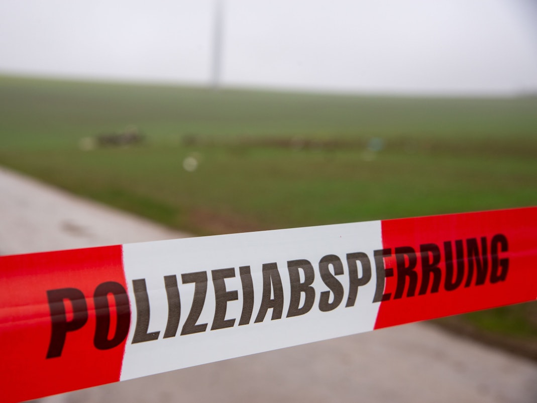 Ein Flatterband der Polizei mit dem Schriftzug «Polizeiabsperrung» sperrt eine Straße an einer Unfallstelle nach dem Absturz eines Kleinflugzeugs.