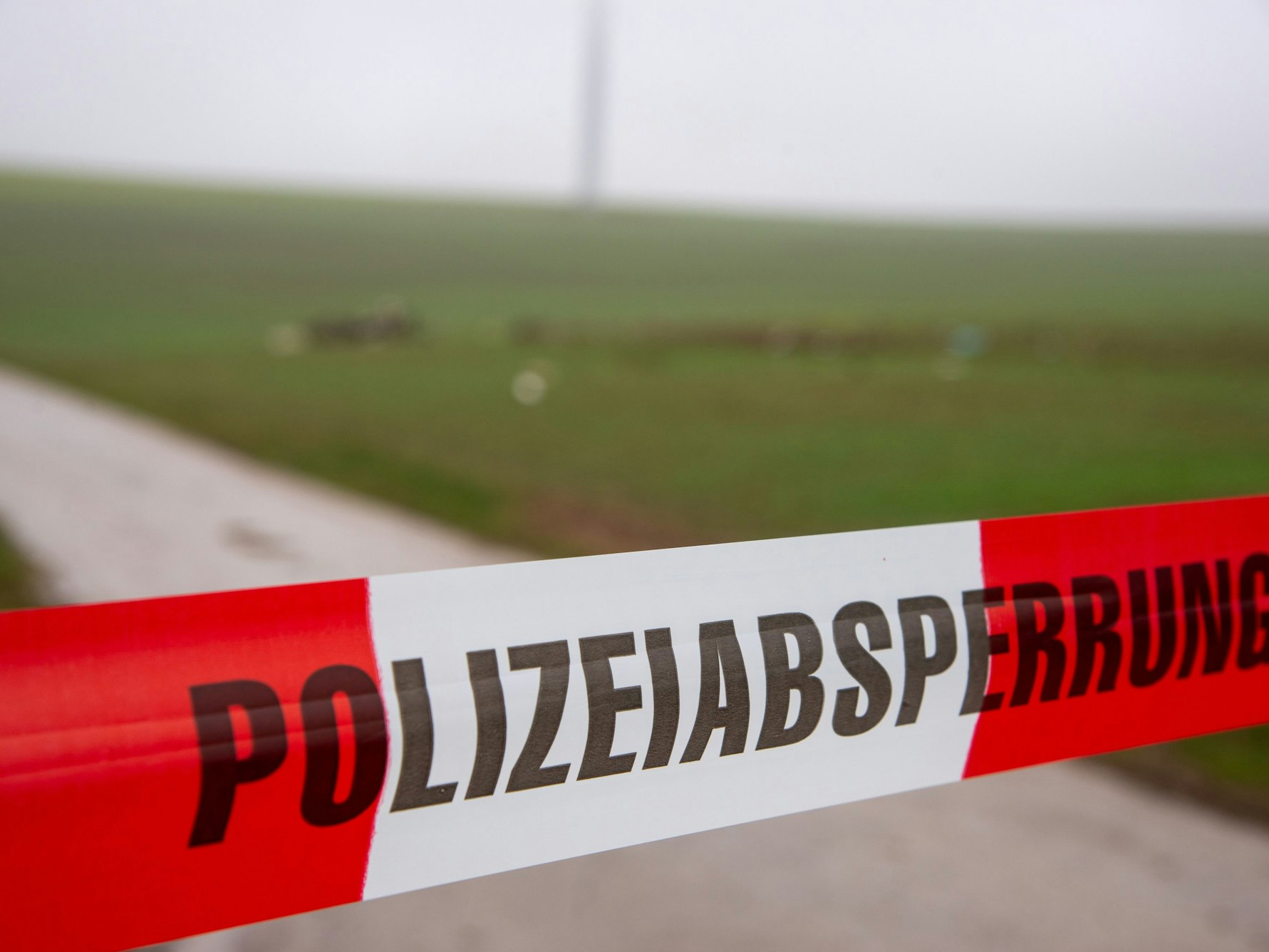Ein Flatterband der Polizei mit dem Schriftzug «Polizeiabsperrung» sperrt eine Straße an einer Unfallstelle nach dem Absturz eines Kleinflugzeugs.