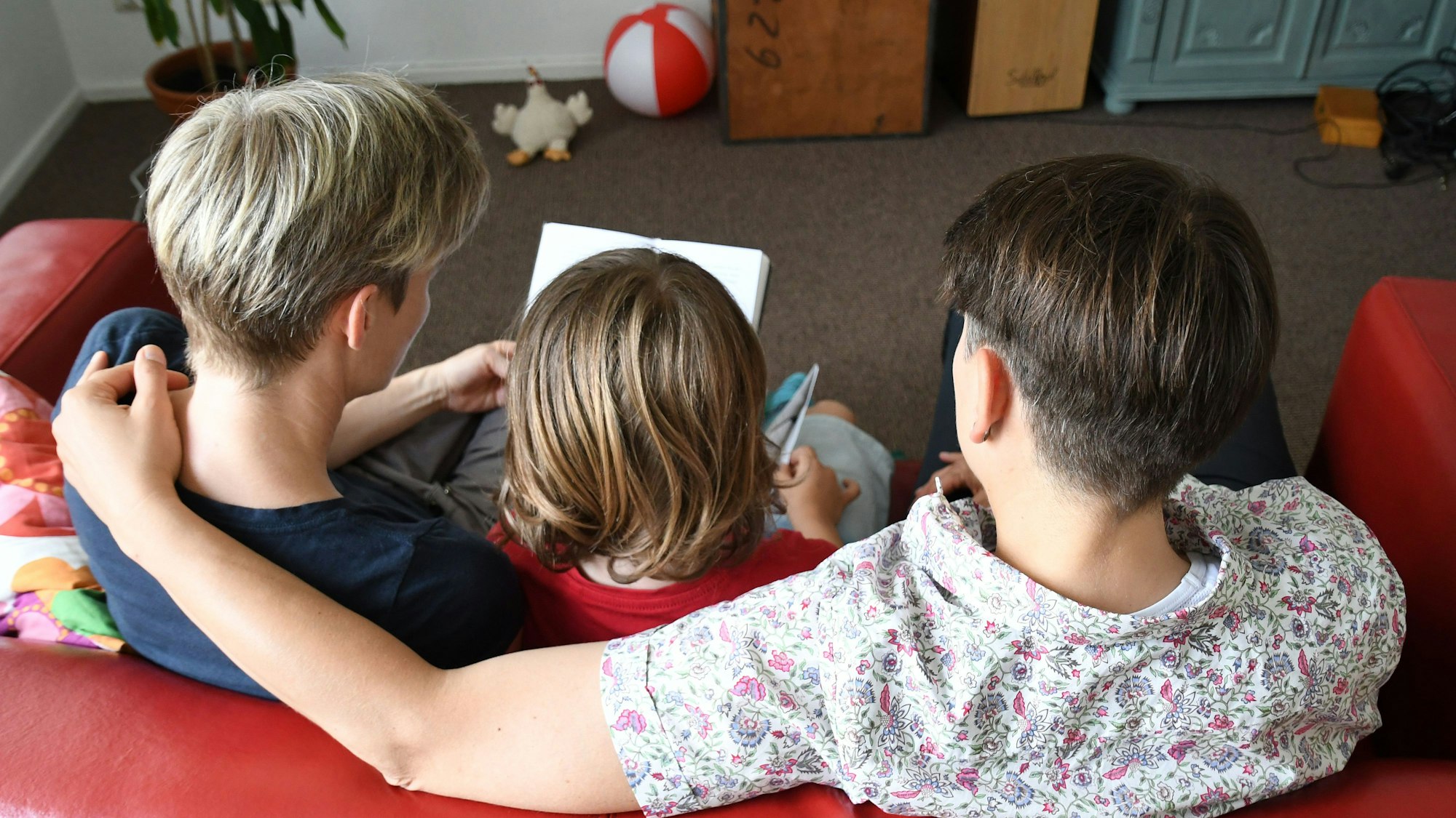 Ein miteinander verheiratetes lesbisches Paar sitzt am 24.06.2016 in Bremen mit seinem Sohn auf dem Sofa und liest in einem Buch.