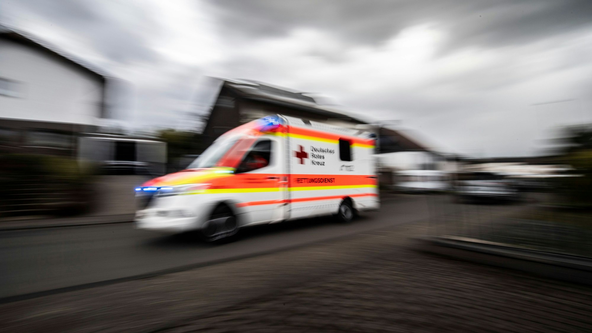 Rettungswagen fährt mit hoher Geschwindigkeit durch eine Straße.