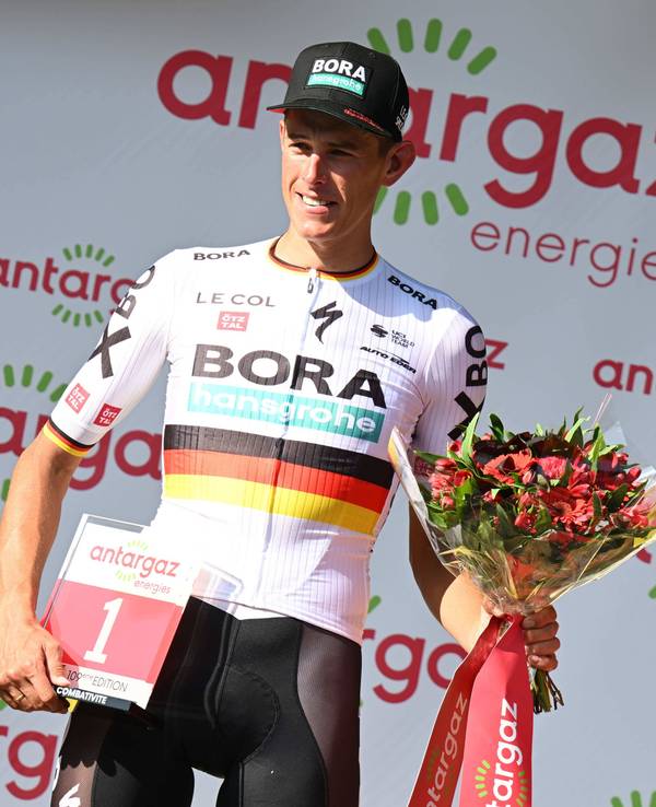 Nils Politt posiert mit der roten Startnummer und einem Strauß Blumen.