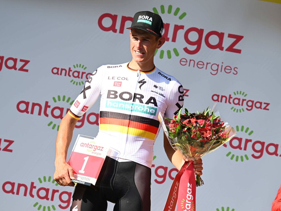 Nils Politt posiert mit der roten Startnummer und einem Strauß Blumen.