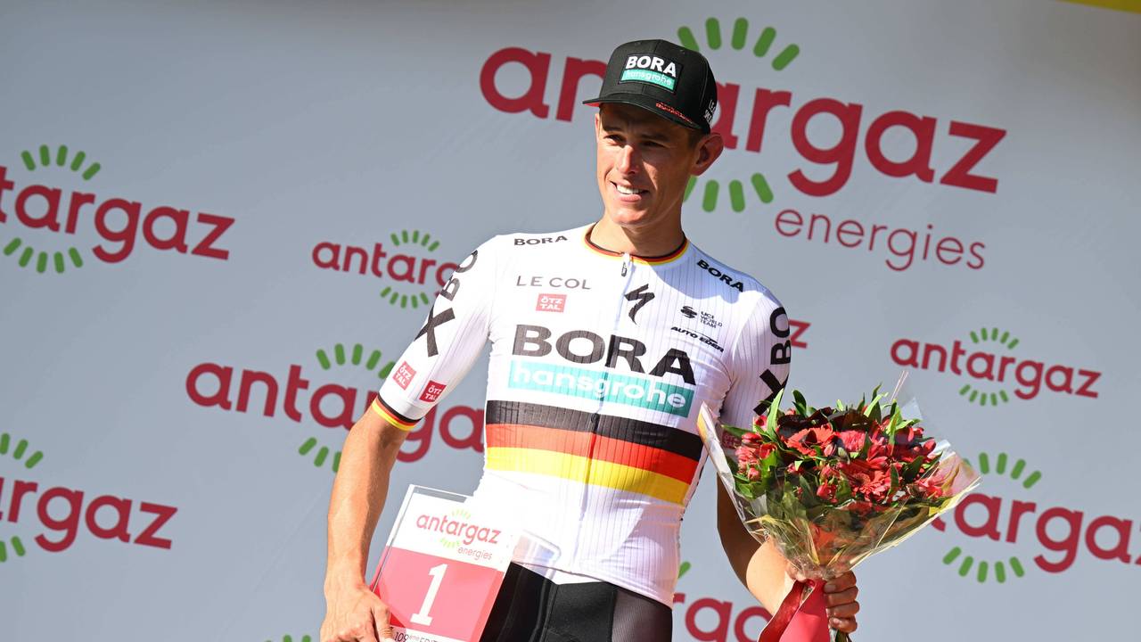 Nils Politt posiert mit der roten Startnummer und einem Strauß Blumen.