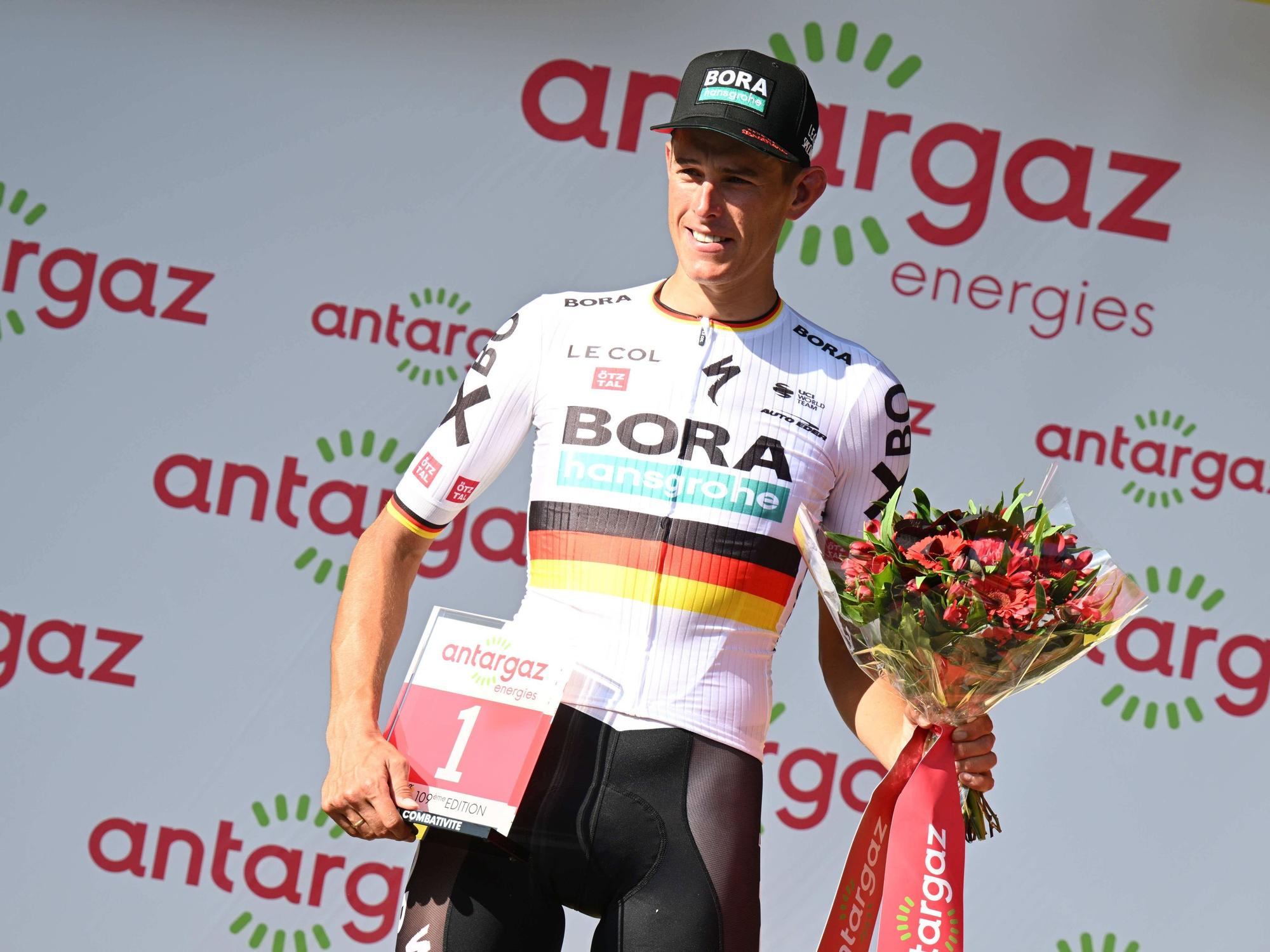 Nils Politt posiert mit der roten Startnummer und einem Strauß Blumen.