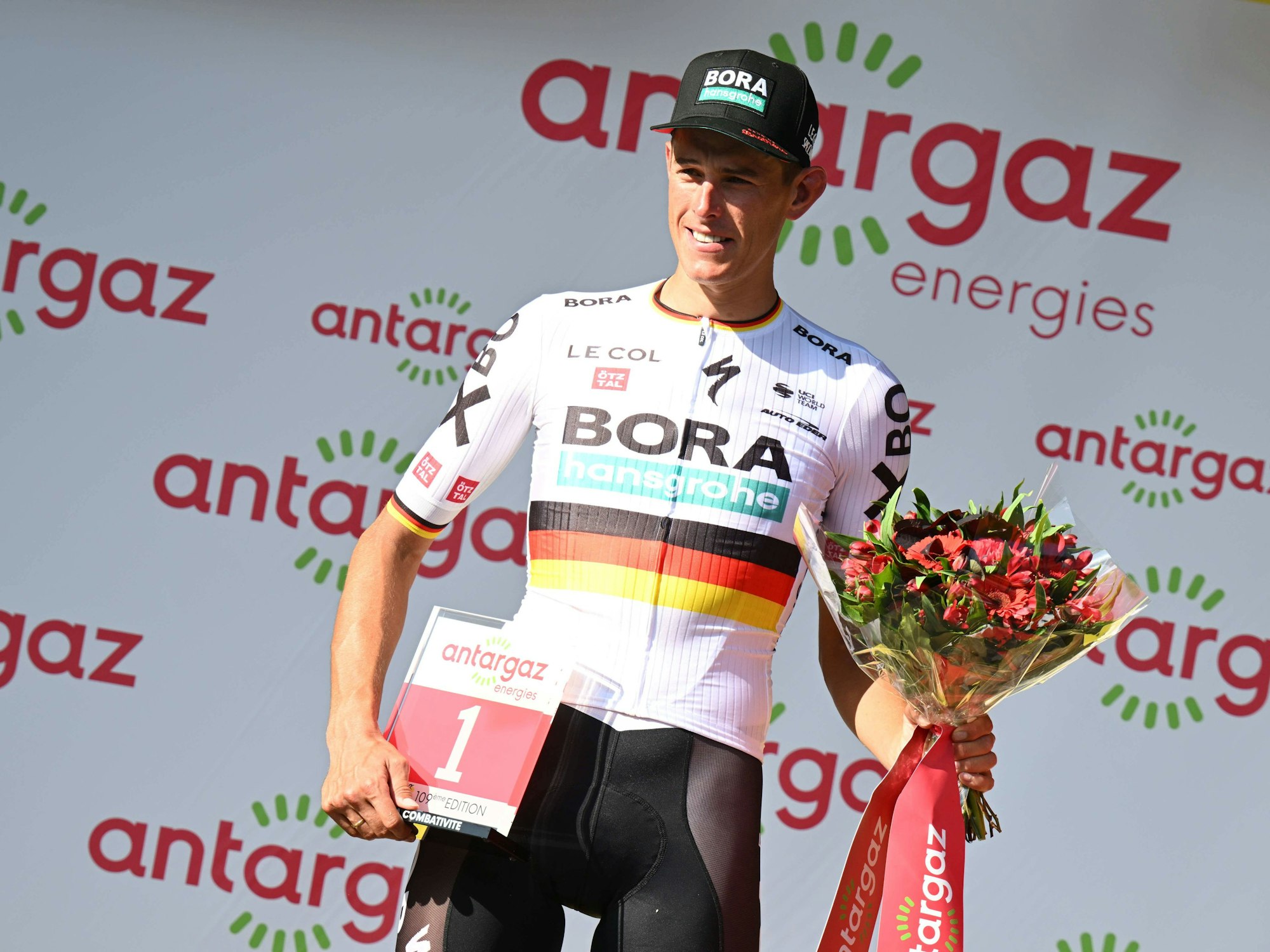 Nils Politt posiert mit der roten Startnummer und einem Strauß Blumen.