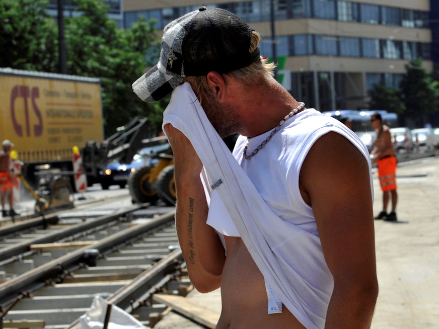 Ein Straßenarbeiter wischt sich am Montag (12.07.2010) in der Grillparzerstraße im Stadtteil Haidhausen in München (Oberbayern) bei großer Hitze den Schweiß ab.