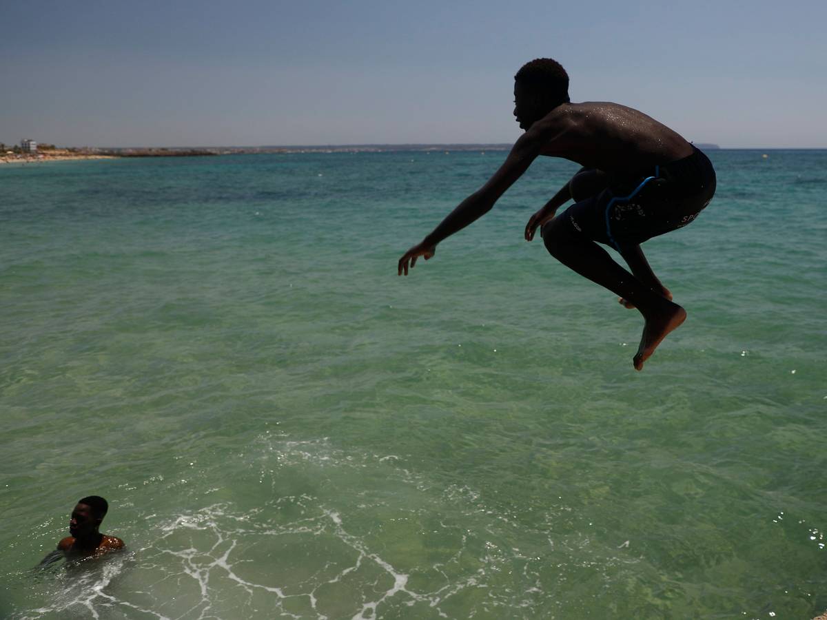 Ein Junge springt während der Hitzewelle am Strand Can Pere Antoni ins Meer.