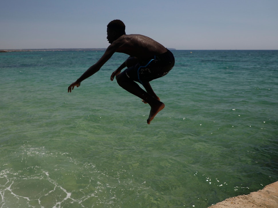 Ein Junge springt während der Hitzewelle am Strand Can Pere Antoni ins Meer.