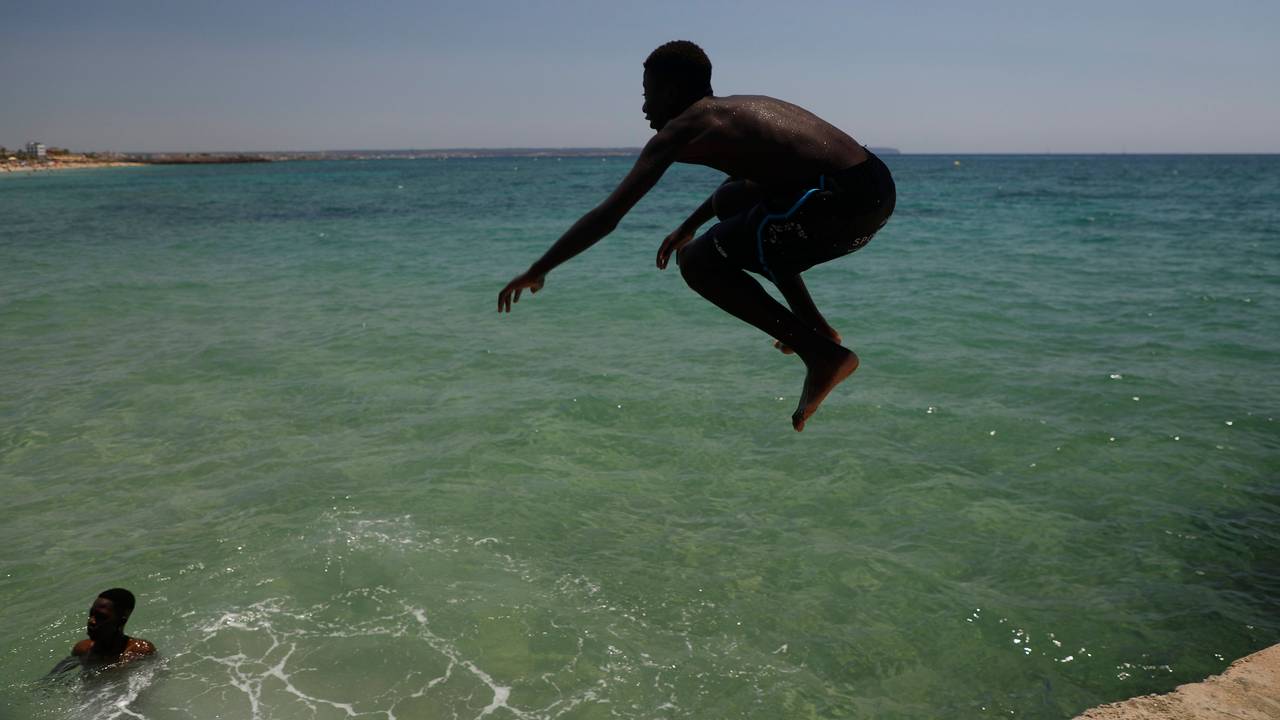 Ein Junge springt während der Hitzewelle am Strand Can Pere Antoni ins Meer.