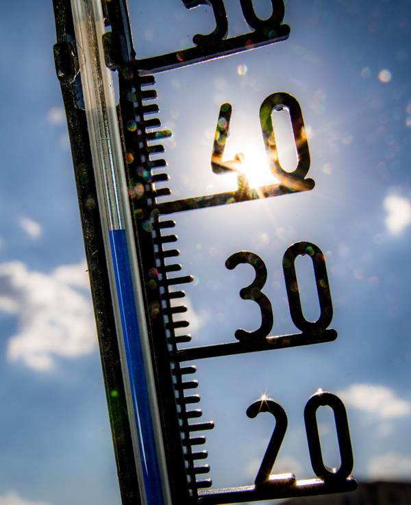 Ein Thermometer an einer Hauswand zeigt Temperaturen in Richtung der 40-Grad-Marke an.