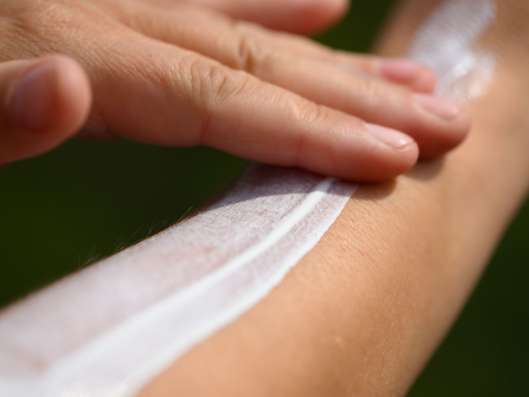 Eine Frau schmiert sich ihren Unterarm mit Sonnencreme ein.