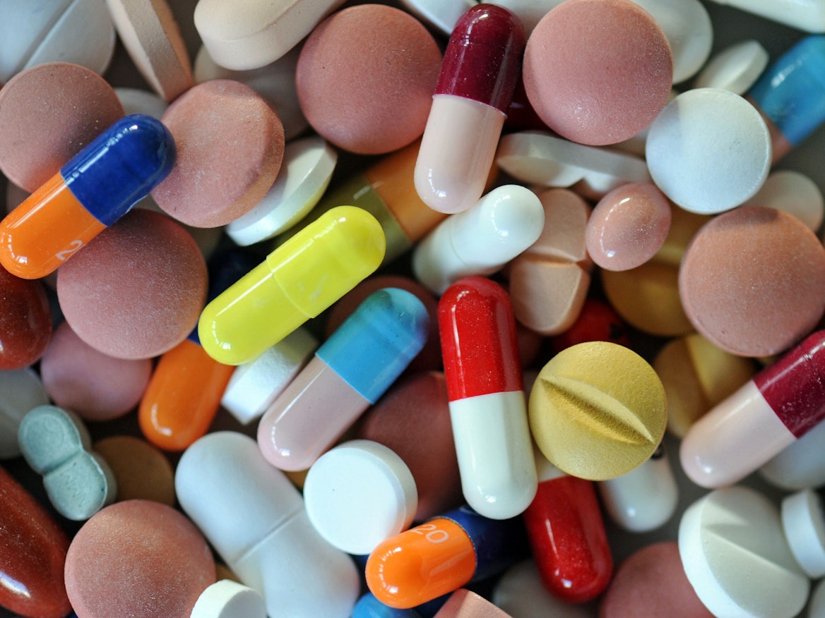 Verschiedene Pillen und Tabletten liegen auf einem Teller.