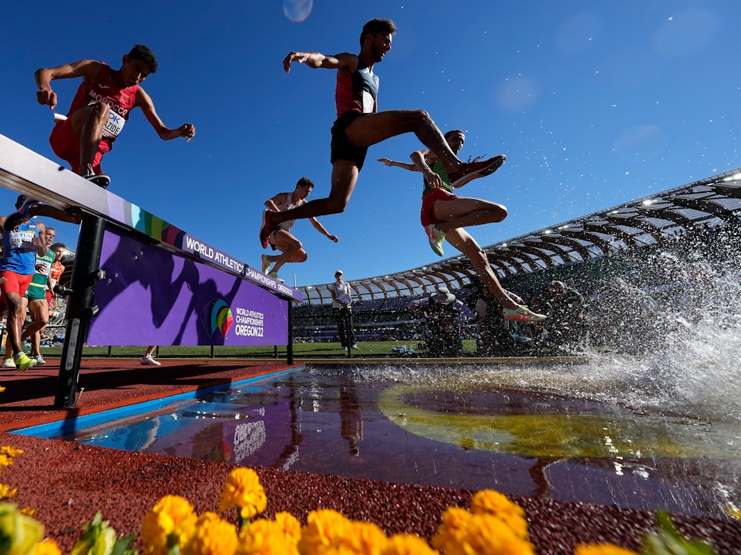 Die Läufer überqueren ein Hindernis und springen in einen Wassergraben.