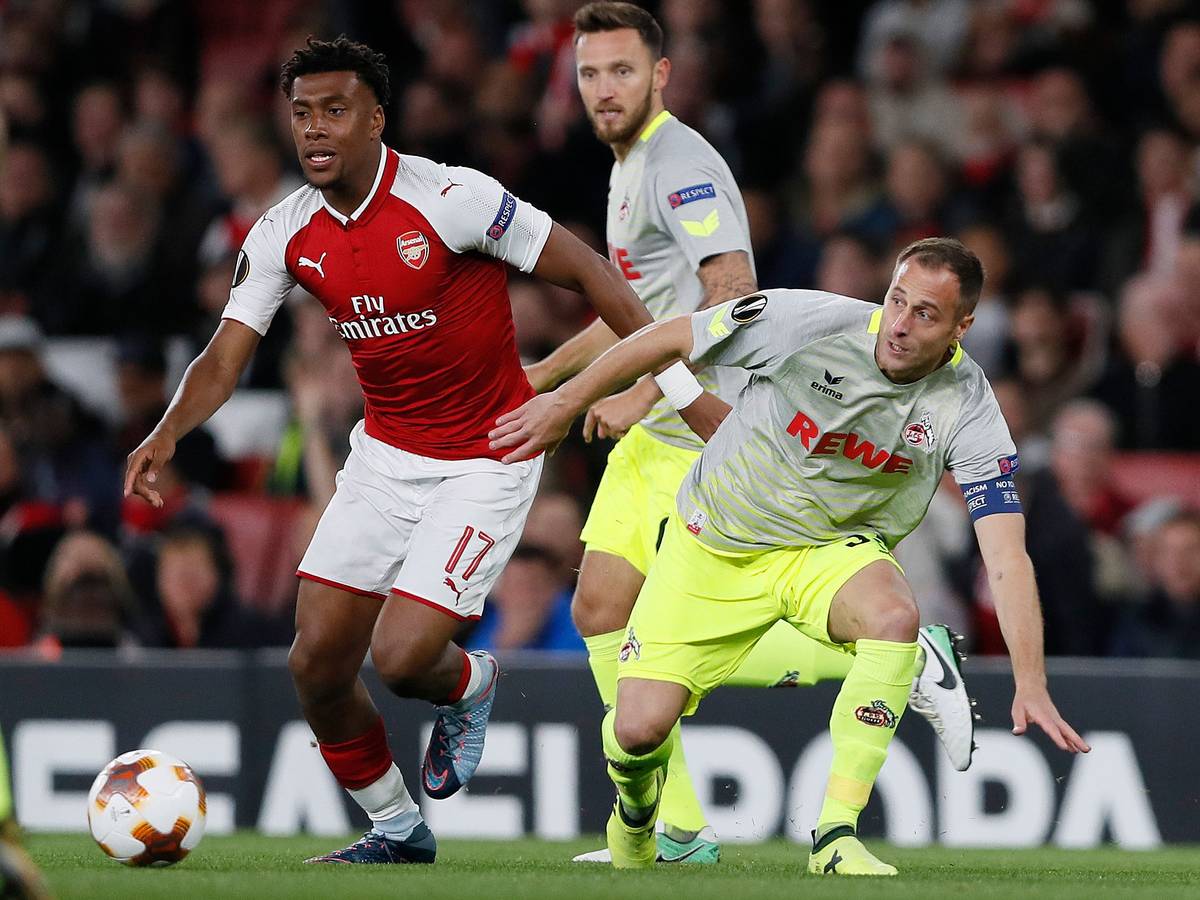 Alex Iwobi im roten Arsenal-Trikot hat den Ball, Matthias Lehmann ist in seiner Nähe, verliert aber das Gleichgewicht. Im Hintergrund ist Marco Höger zu sehen.
