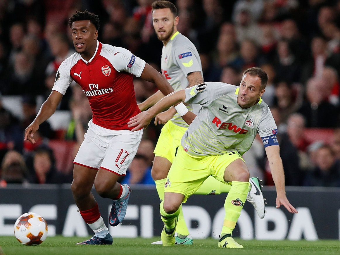 Alex Iwobi im roten Arsenal-Trikot hat den Ball, Matthias Lehmann ist in seiner Nähe, verliert aber das Gleichgewicht. Im Hintergrund ist Marco Höger zu sehen.