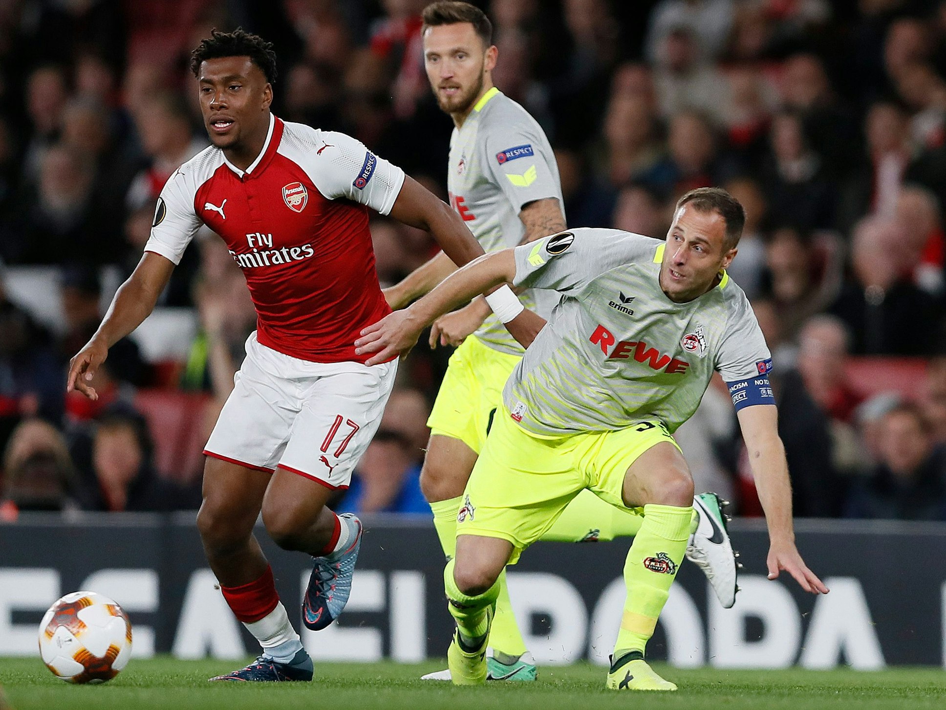 Alex Iwobi im roten Arsenal-Trikot hat den Ball, Matthias Lehmann ist in seiner Nähe, verliert aber das Gleichgewicht. Im Hintergrund ist Marco Höger zu sehen.