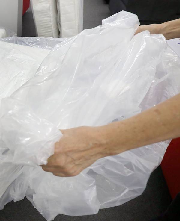 Eine Frau packt eine neue Matratze aus der Verpackungsfolie aus.