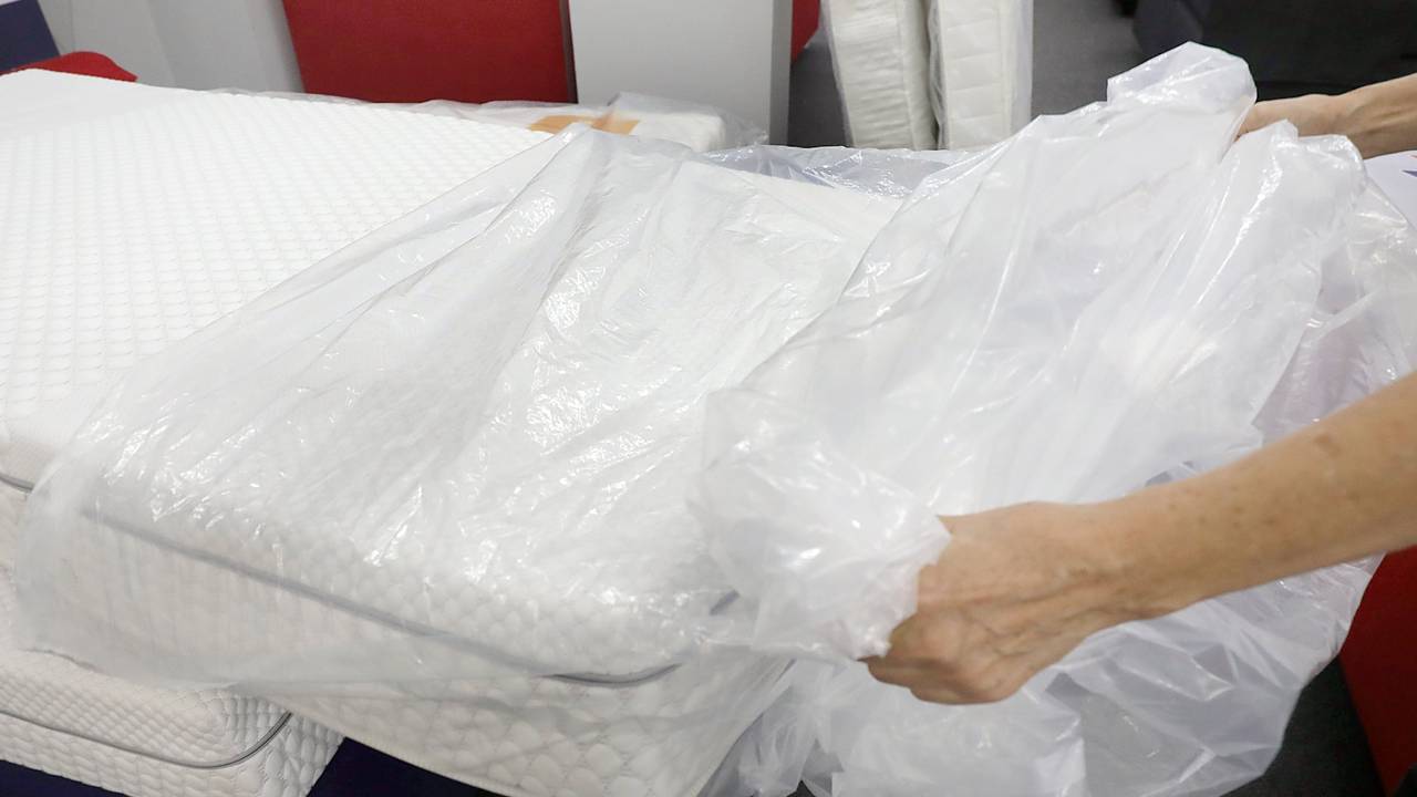 Eine Frau packt eine neue Matratze aus der Verpackungsfolie aus.