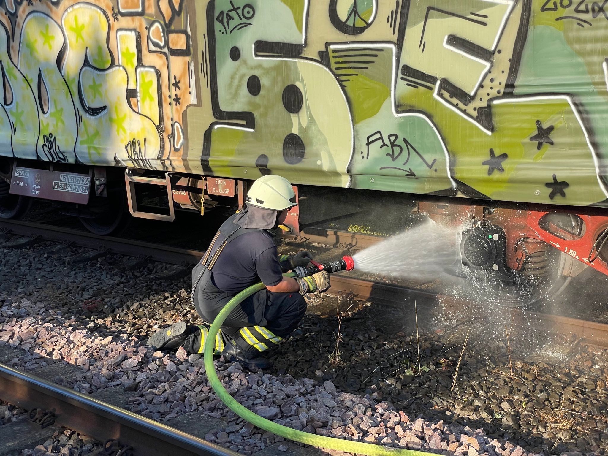 Am 20. Juli 2022 löscht ein Feuerwehrmann die glühende Bremse eines Güterzugs.