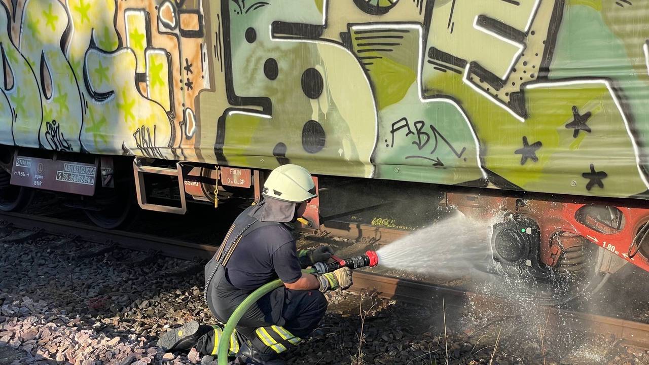 Am 20. Juli 2022 löscht ein Feuerwehrmann die glühende Bremse eines Güterzugs.